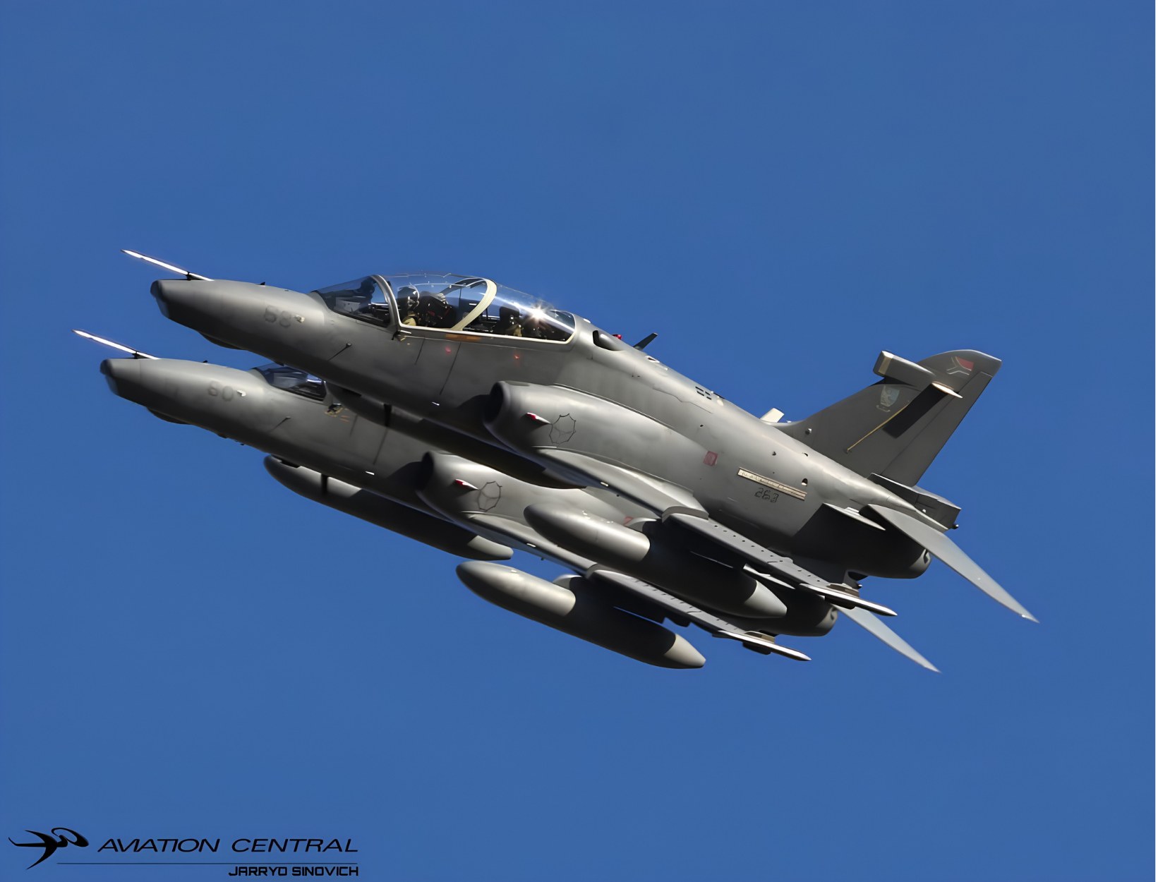 Two South African Air Force Hawk jets flying in tight formation against a blue sky