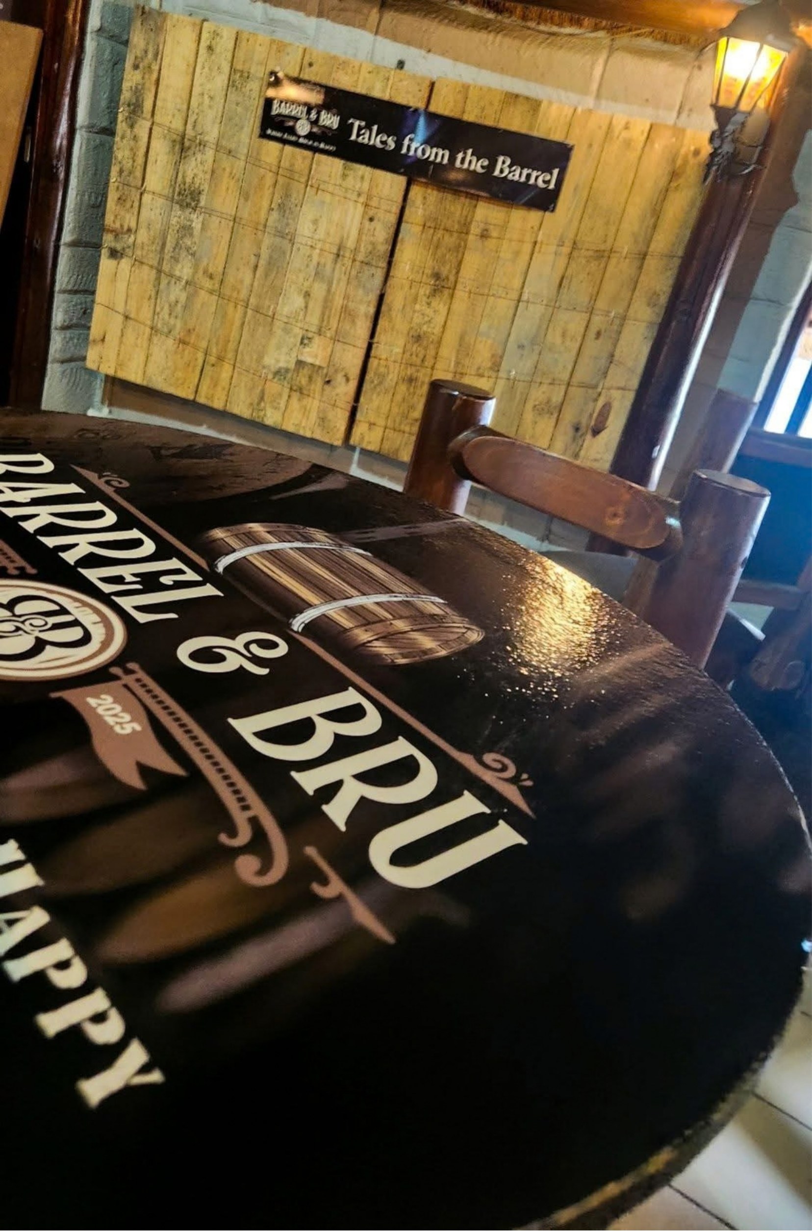 A Barrel & Bru branded table top inside the bar, with a Tales from the Barrel sign on the timber wall